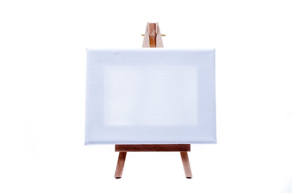 Photograph of an easel holding a blank canvas, before pieces are layered onto it