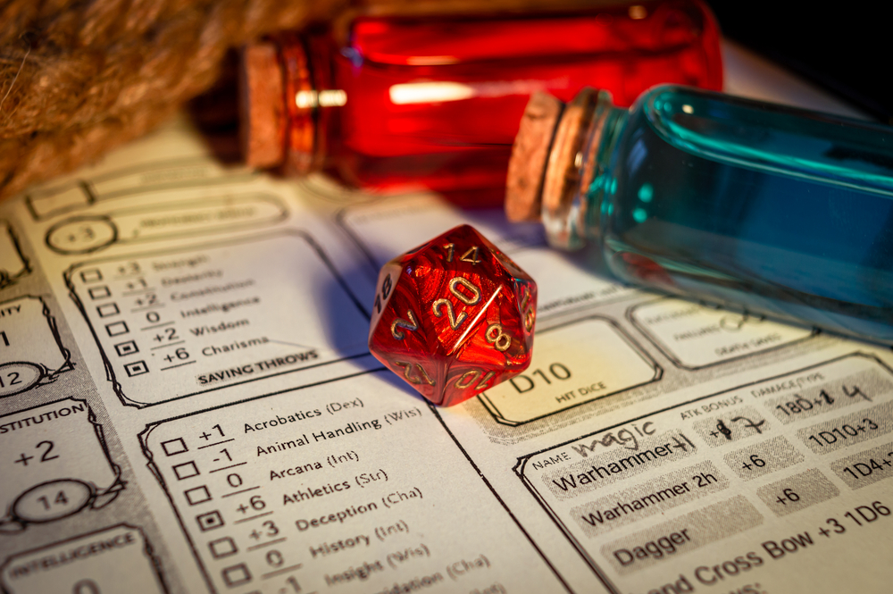 Close-up image of a red 20-sided role-playing gaming die on a character sheet. Within the background magic potions