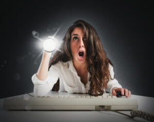 writer at her keyboard with a flashlight looking amazed