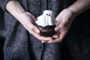 hands carrying a cupcake with a ghost on top