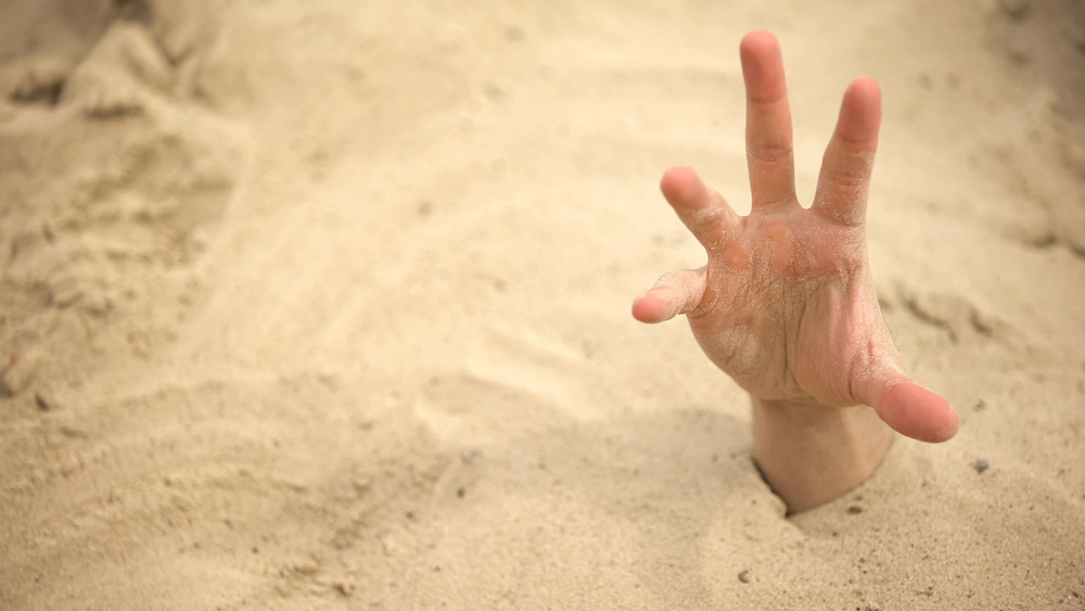 hand reaching out of quick sand