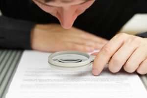 Writer looking at document through a magnifying glass