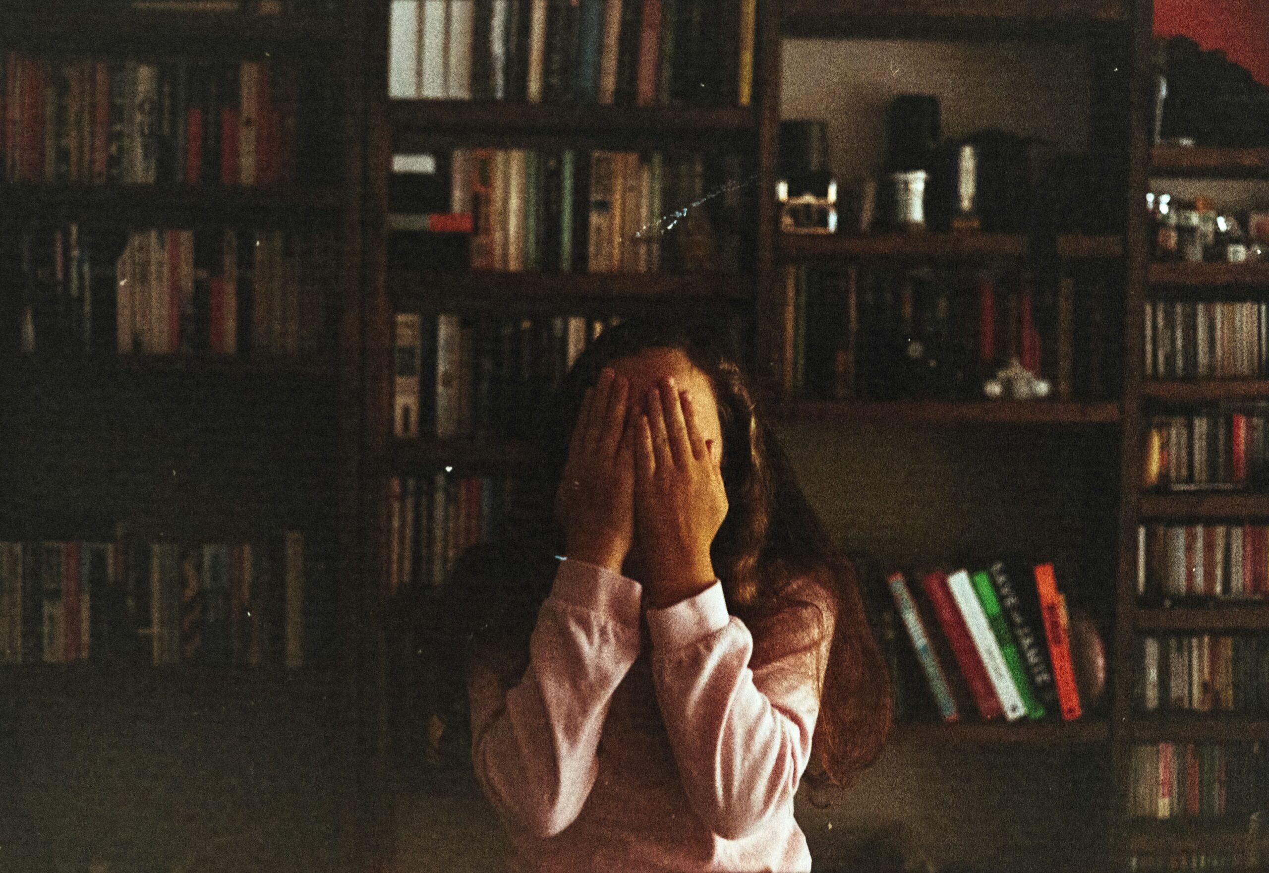 Writer who has been affected by scams. Sitting in a library, head in hands.