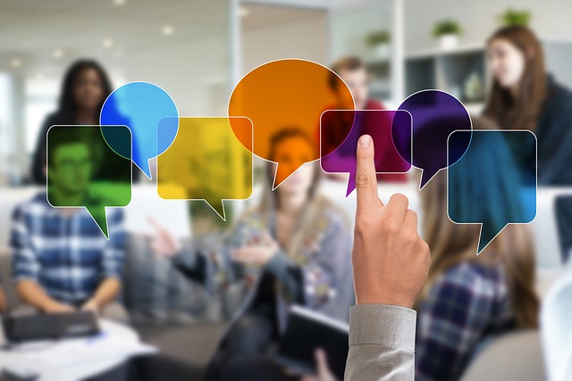 Several people conversing in a room, one person presses on one of a few colorful speech bubbles.