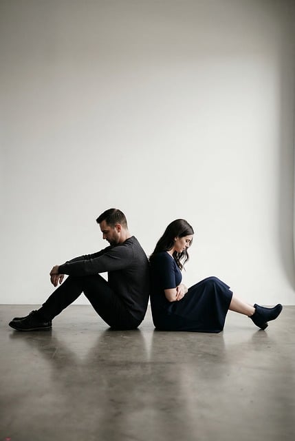 Two people in conflict, sitting back-to-back.