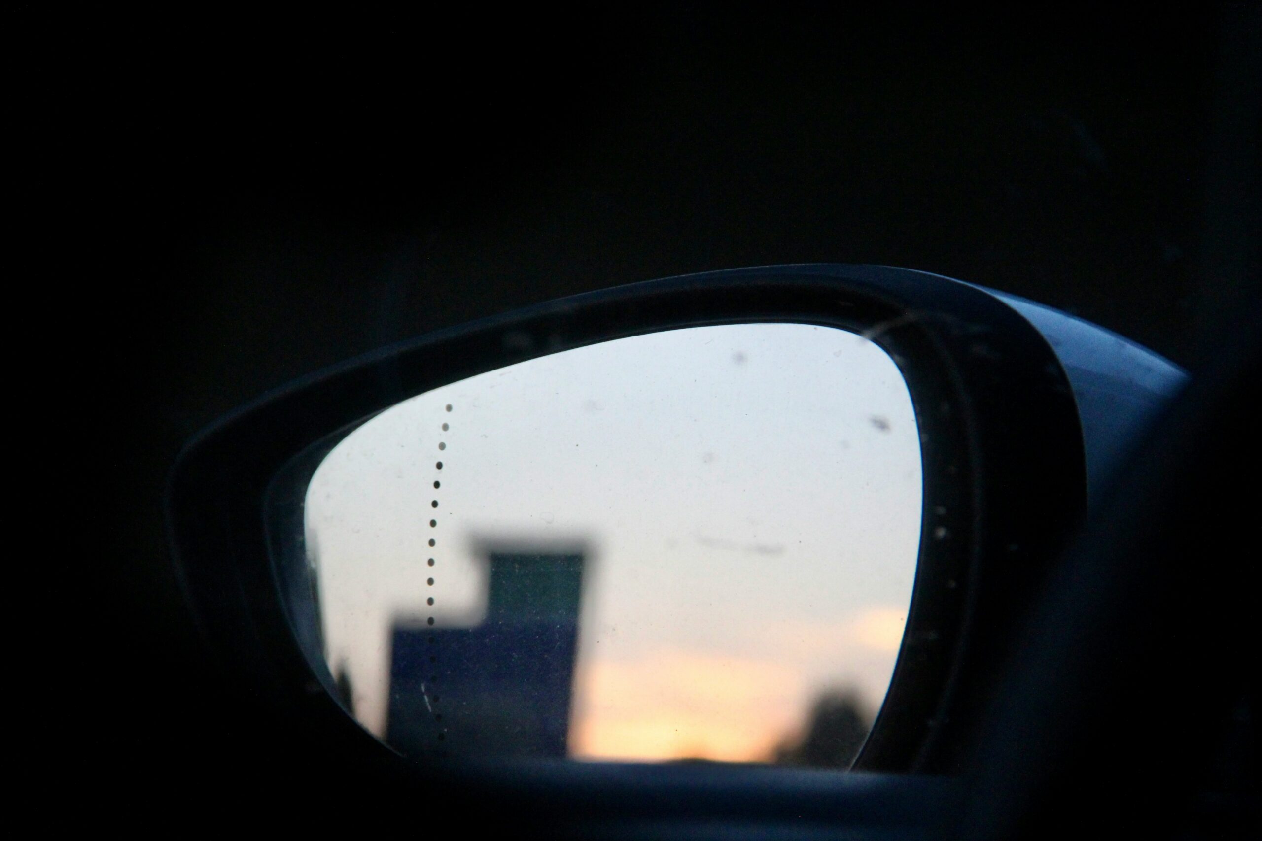 Blurry image of a city in a car side mirror.